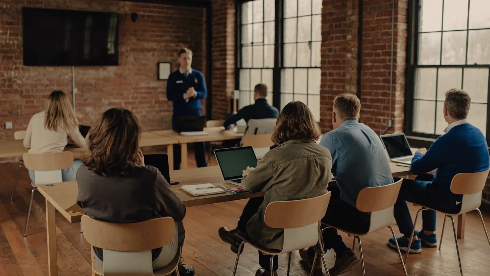 Employees in a training session in a brick-walled New England mill office with tall windows